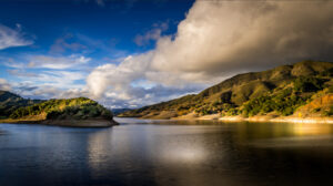 a photo of rolling hills in Autumn along a blue lake at sunrise