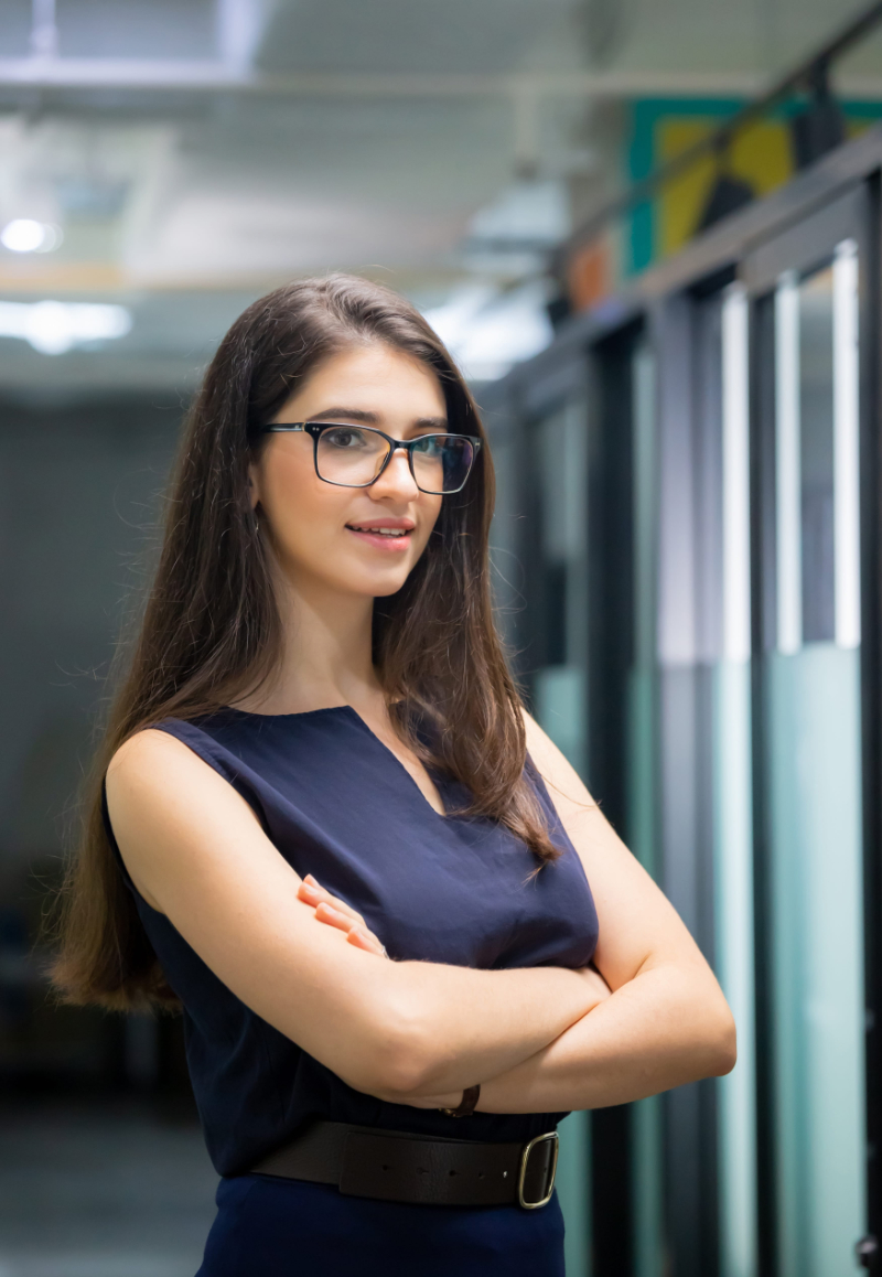 Cheerful young business woman standing with arms crossed in office Photo of professional site selector